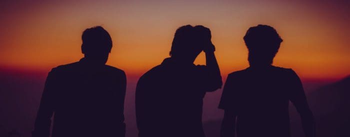 silhouette of 3 men watching sunset